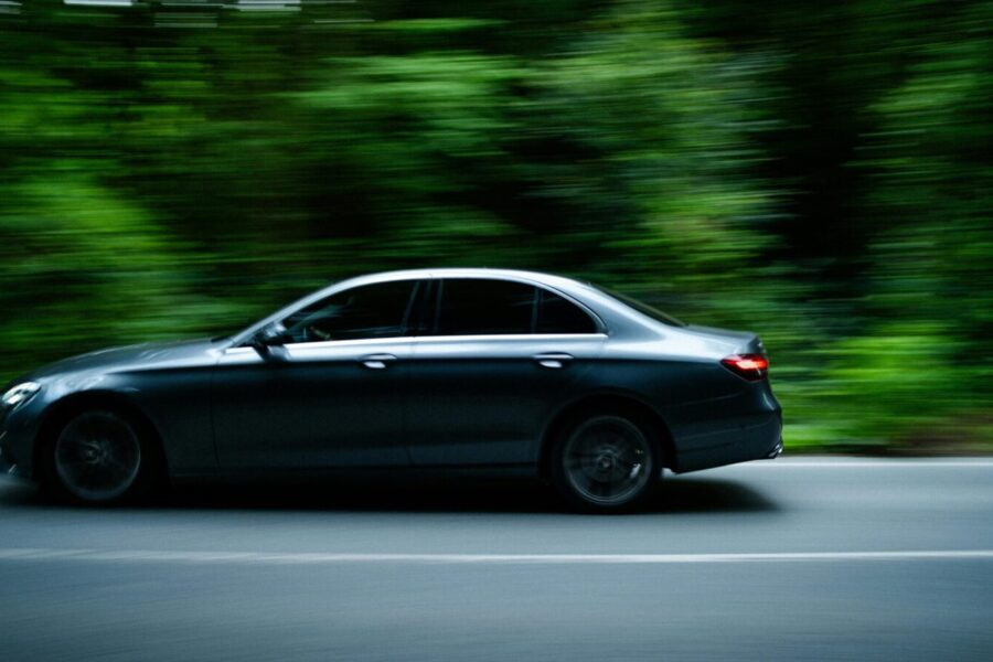 Dynamic shot of a sleek sedan speeding through a lush green forest road in Istanbul.
