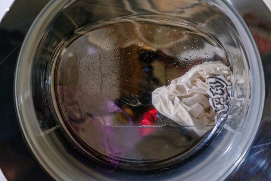 A clear view of wet clothes spinning inside a front-loading washing machine.