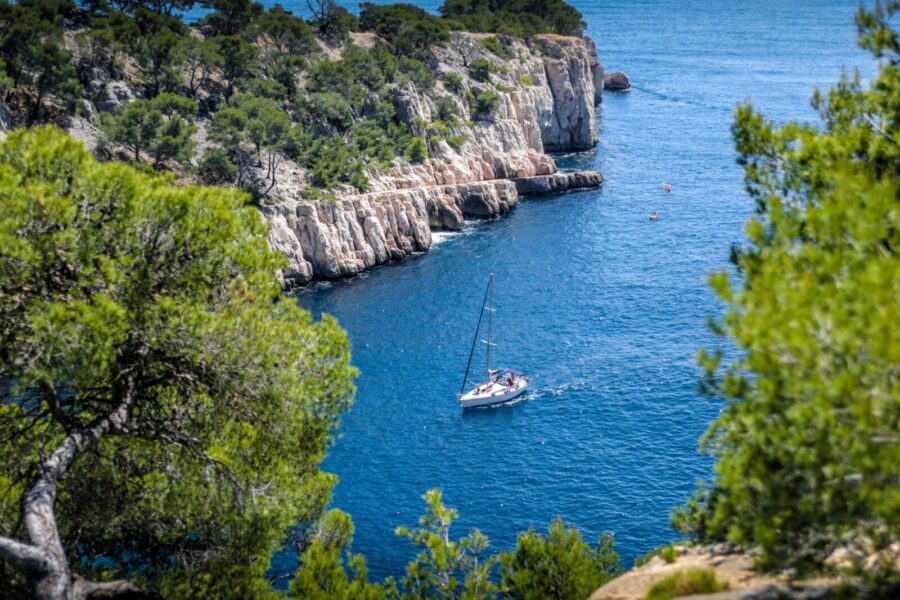 Stunning view of a sailboat navigating the blue waters of Calanques National Park near Marseille.