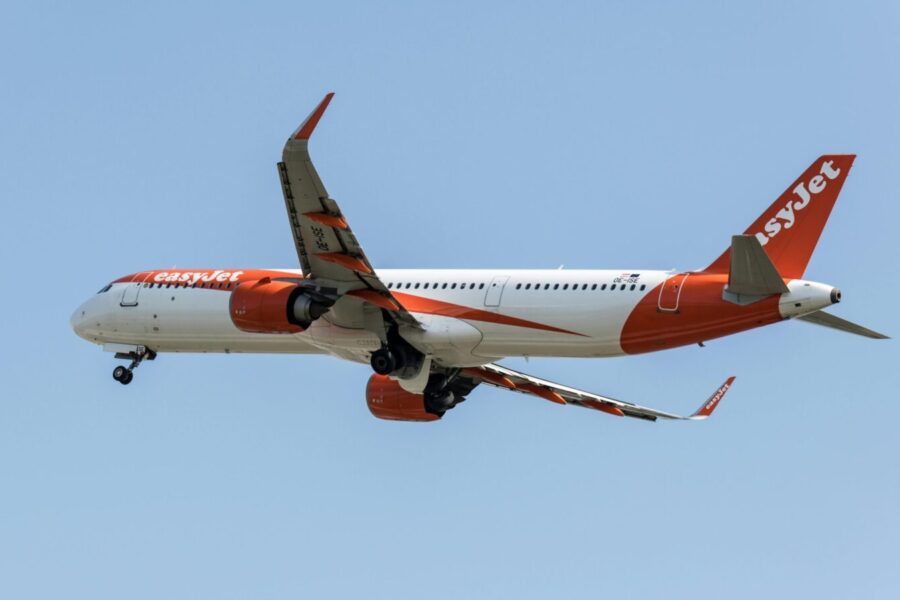 EasyJet aircraft flying above Prague during daytime, showcasing modern aviation in Europe.