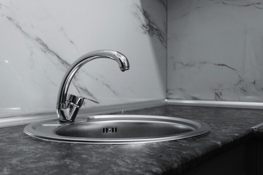 A stylish stainless steel kitchen faucet with a sleek and modern design set against a marble backsplash.