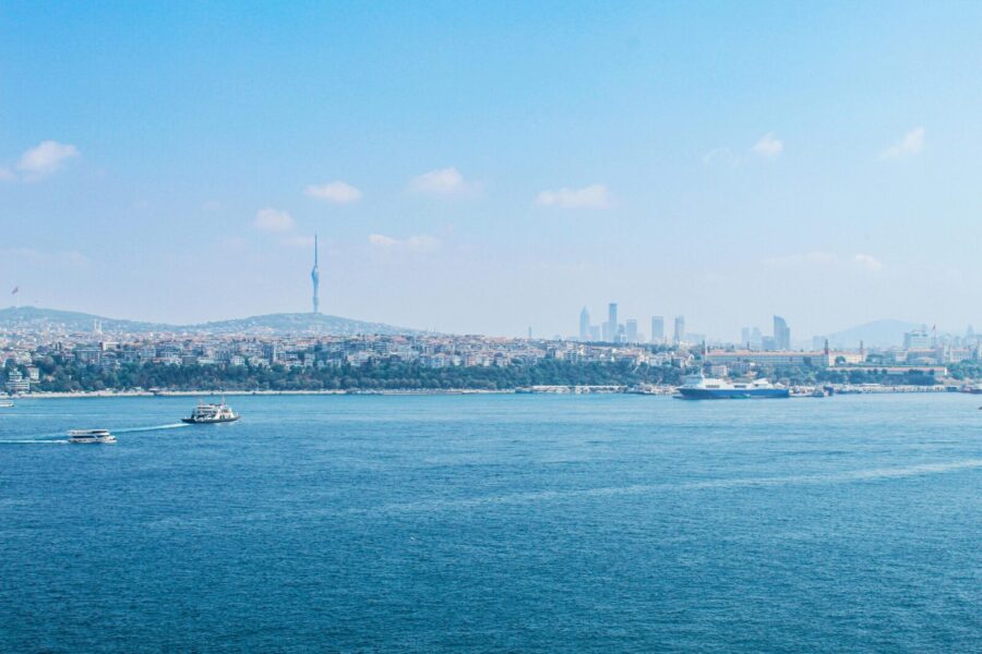 A serene view of the Bosphorus in Istanbul with the city skyline and boats on a sunny day.