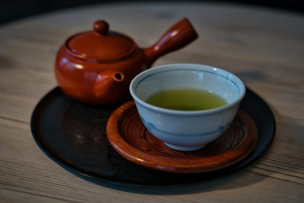 Traditional Japanese teapot and cup of green tea on a wooden table.