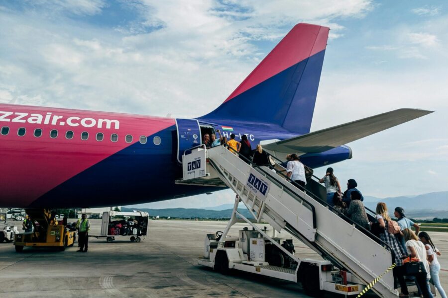 Travelers boarding a WizzAir Airbus A320 jet on a clear day at the airport.
