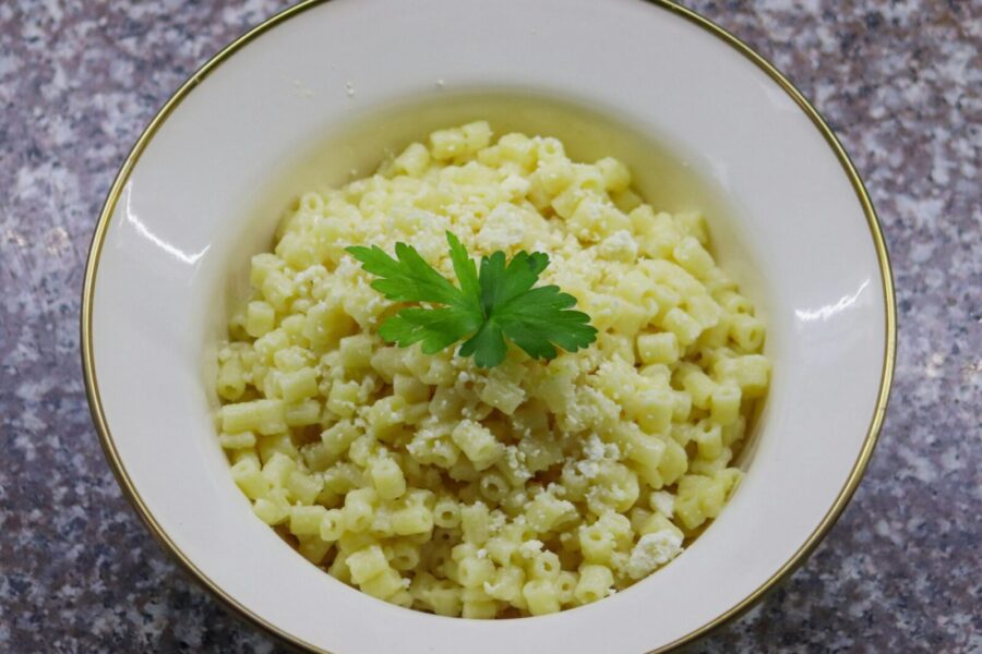 Close-up of creamy Parmesan pasta topped with fresh parsley in a white bowl.