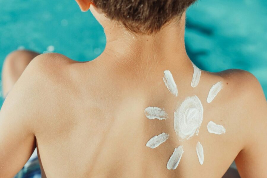 Child's back with sunscreen in sun shape, enjoying a sunny day by the pool.