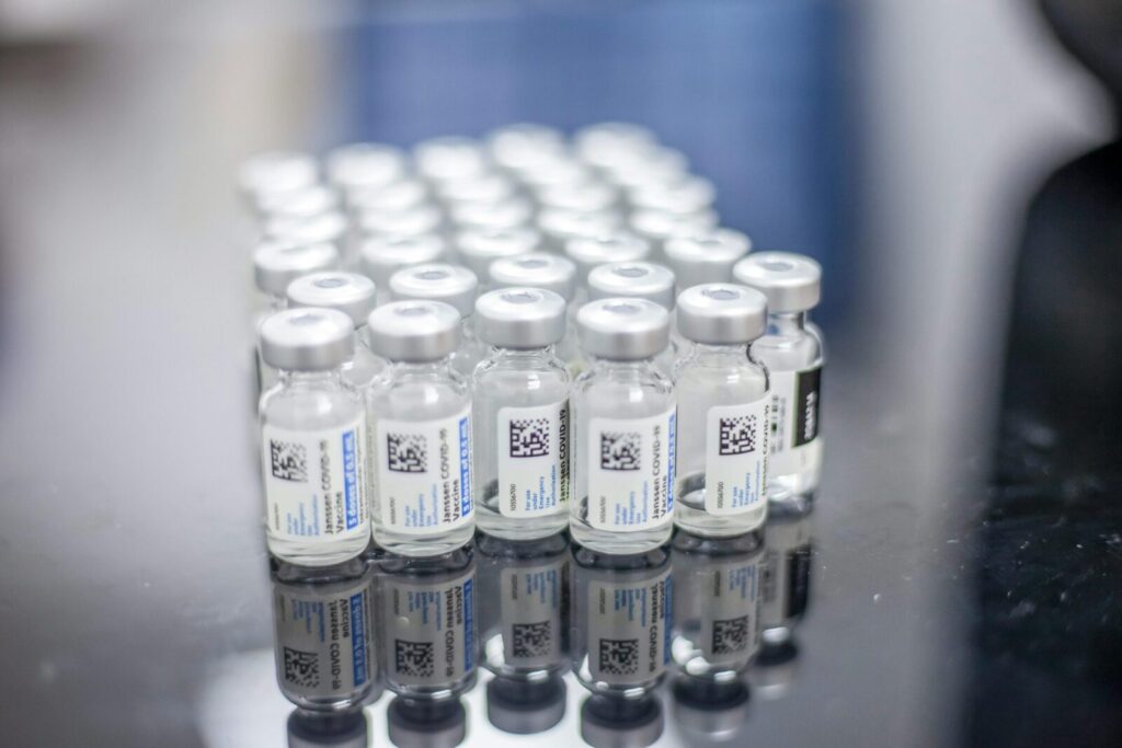 Close-up of multiple Covid-19 vaccine vials arranged on a reflective table.
