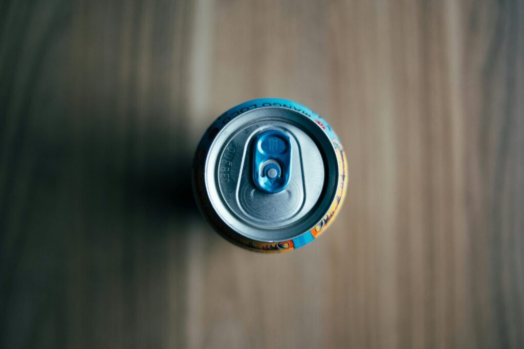 Aerial shot of a beverage can on a wooden table, highlighting the pull tab for refreshment.