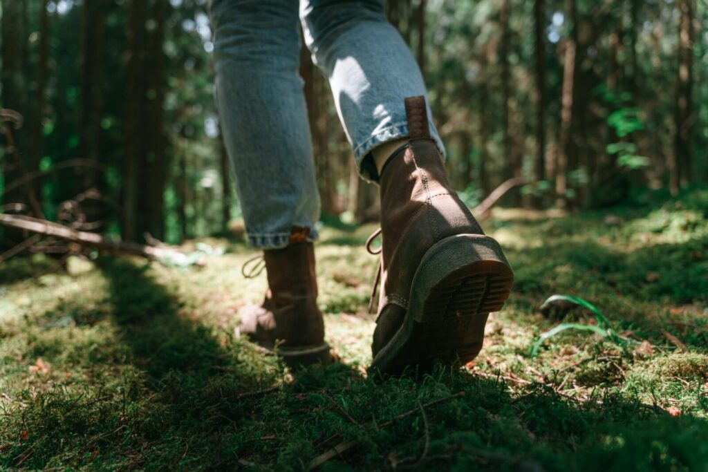 Explore nature with this close-up shot of a hiker's boots navigating a lush forest trail.