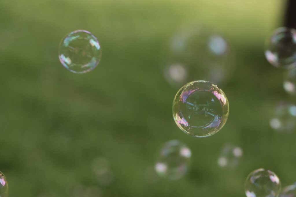 Colorful soap bubbles floating in a garden, reflecting light on a sunny day.